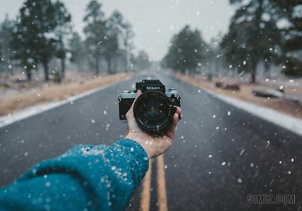 在下着雪的马路上一只手拿着一台相机背景图片