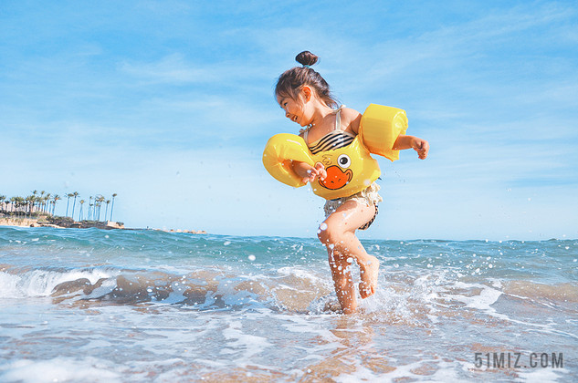 蓝色假期旅游海边沙滩小女孩开心玩水女童背景图片
