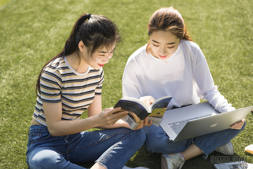 学生朋友在草坪上交流读书图片