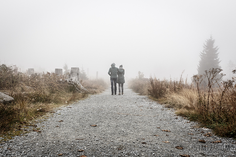 灰黄自然神秘朦胧男女手挽手走在山间小路上山野情侣背景图片